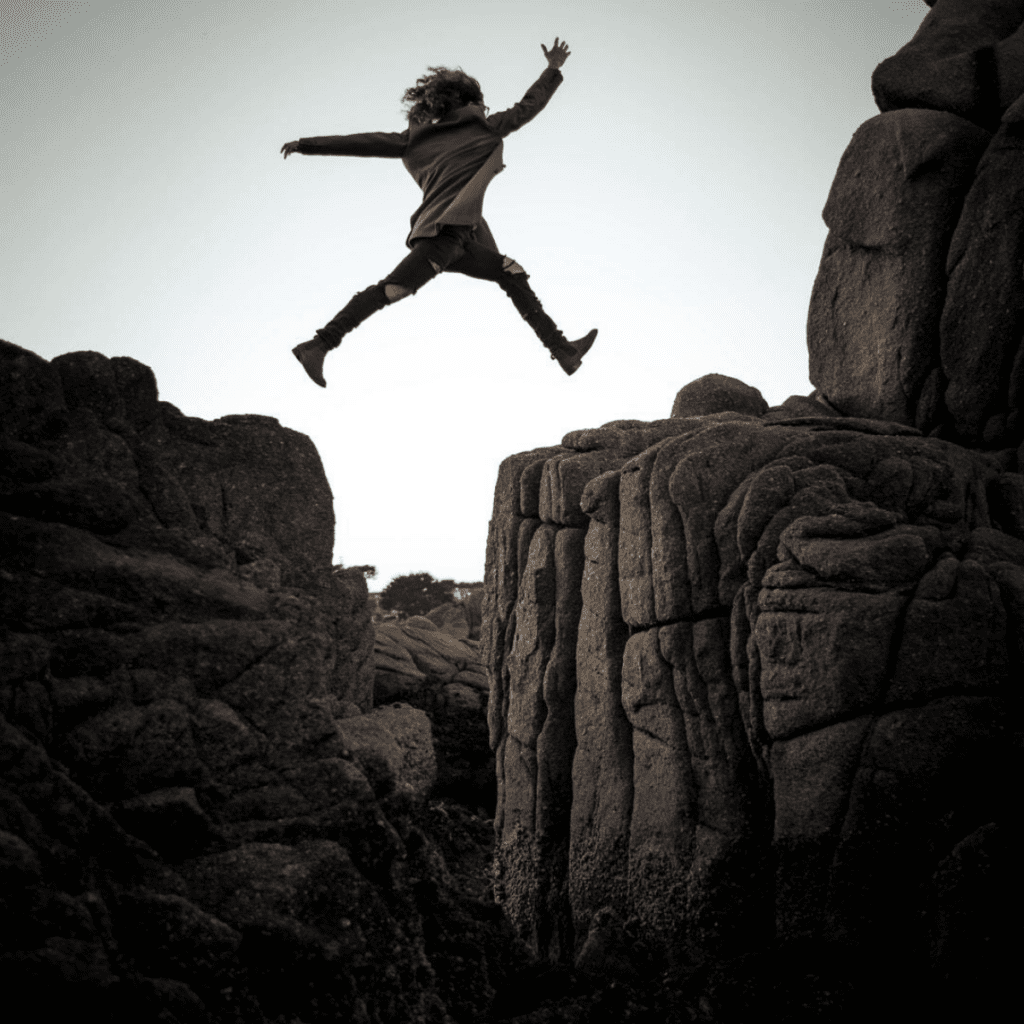 A person jumping in the air over rocks.