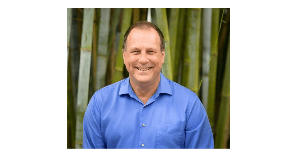 A man in blue shirt smiling for the camera.