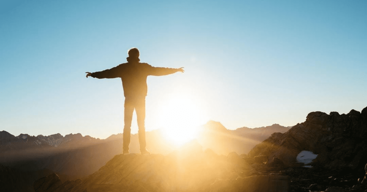 A person standing on top of a mountain with arms outstretched.