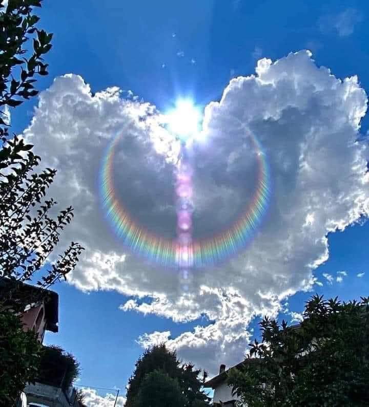 A heart shaped cloud with a rainbow in the middle of it.