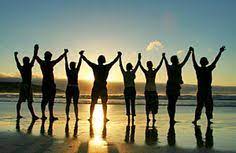 A group of people standing on the beach with their hands up.