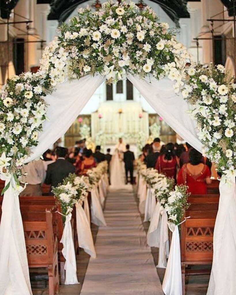 A wedding ceremony with white flowers and white chairs.