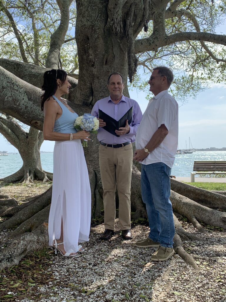 A couple getting married under the tree by the water